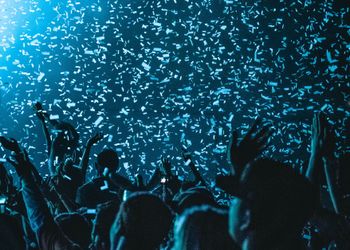 A crowd looking towards a light with confetti in the air
